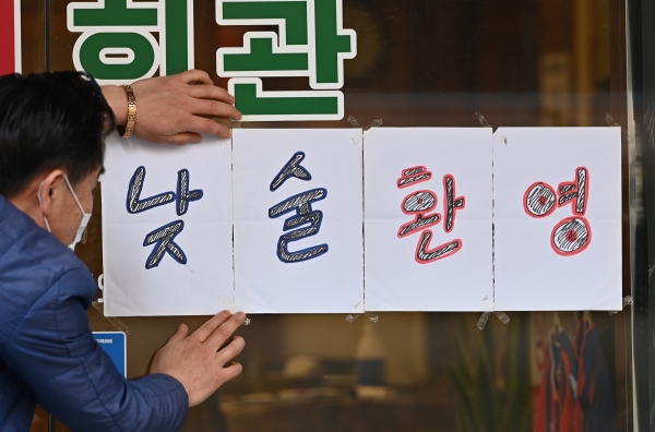 코로나19 대응 수도권 사회적 거리두기를 현행 1.5단계에서 2단계 격상을 하루 앞둔 23일 오후 경기도 수원시 팔달구 인계동 한 음식점에서 주인이 '낮술환영' 안내문을 붙이고 있다.뉴시스