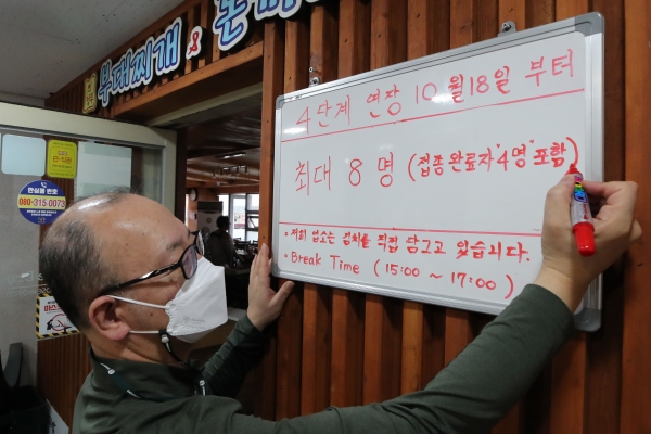 15일 오후 서울 종로구 한 식당점주가 조정된 사회적 거리두기에 따른 변경 인원을 안내하고 있다. 뉴시스